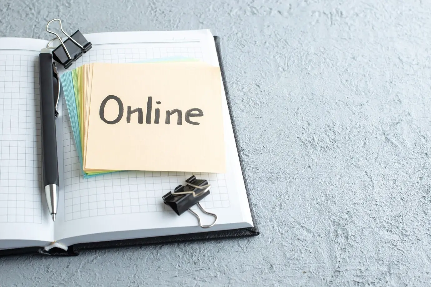 Přední pohled na online napsanou poznámku s perem a poznámkovým blokem na bílém pozadí.